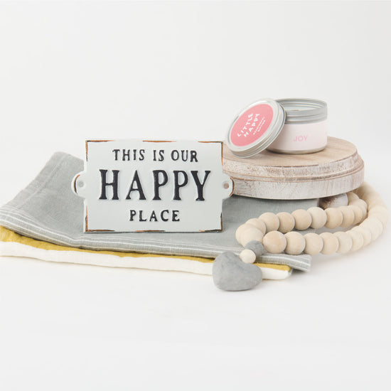 Collection of gift box items includes a candle, happy place sign and wooden beads