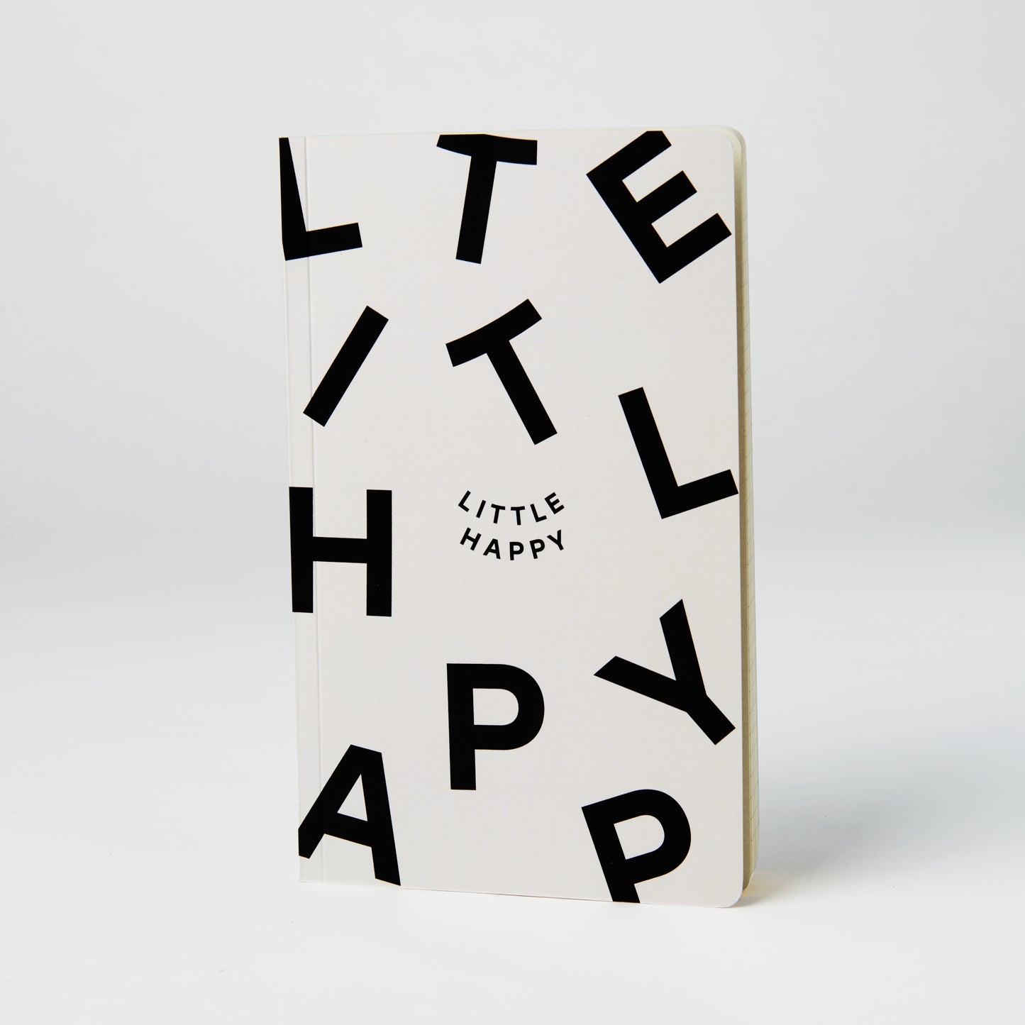 Cream notebook with black lettering saying 'Little Happy'